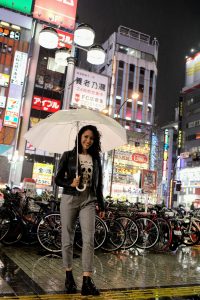 Julia Kanter posing in the rain, in the city with an umbrella