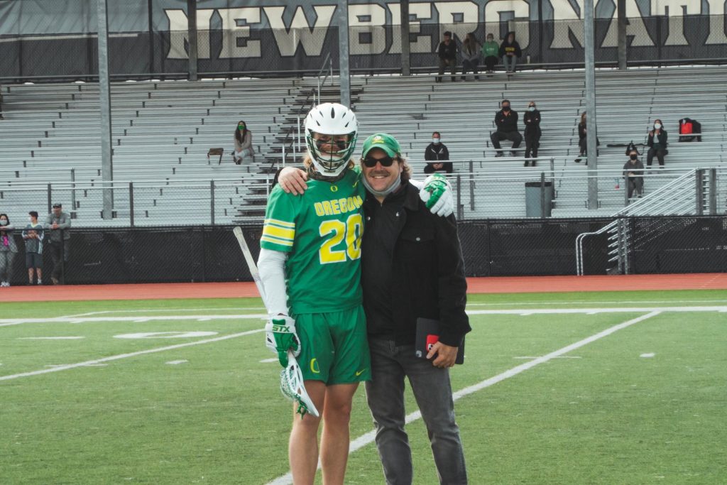 Two Caucasian men smiling at camera on a sports field