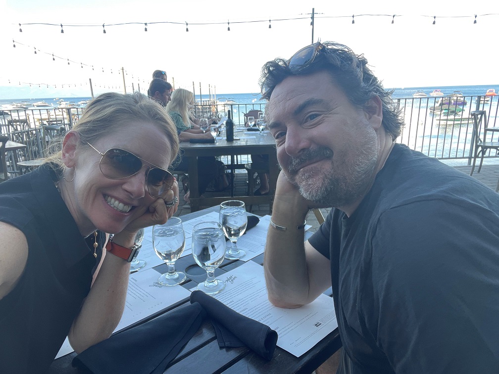 Caucasian woman and man smiling at camera during dinner at an outdoor restaurant